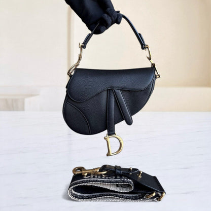 Sac Dior Saddle Small 21 cm en cuir caviar noir avec bandoulière et finitions dorées.