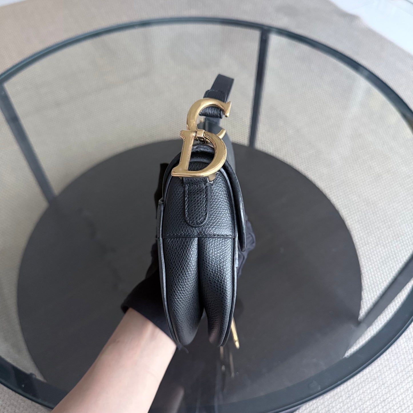 Sac Dior Saddle Small 21 cm en cuir caviar noir avec bandoulière et finitions dorées.