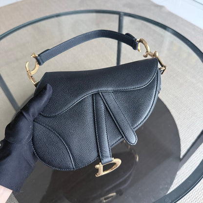 Sac Dior Saddle Small 21 cm en cuir caviar noir avec bandoulière et finitions dorées.